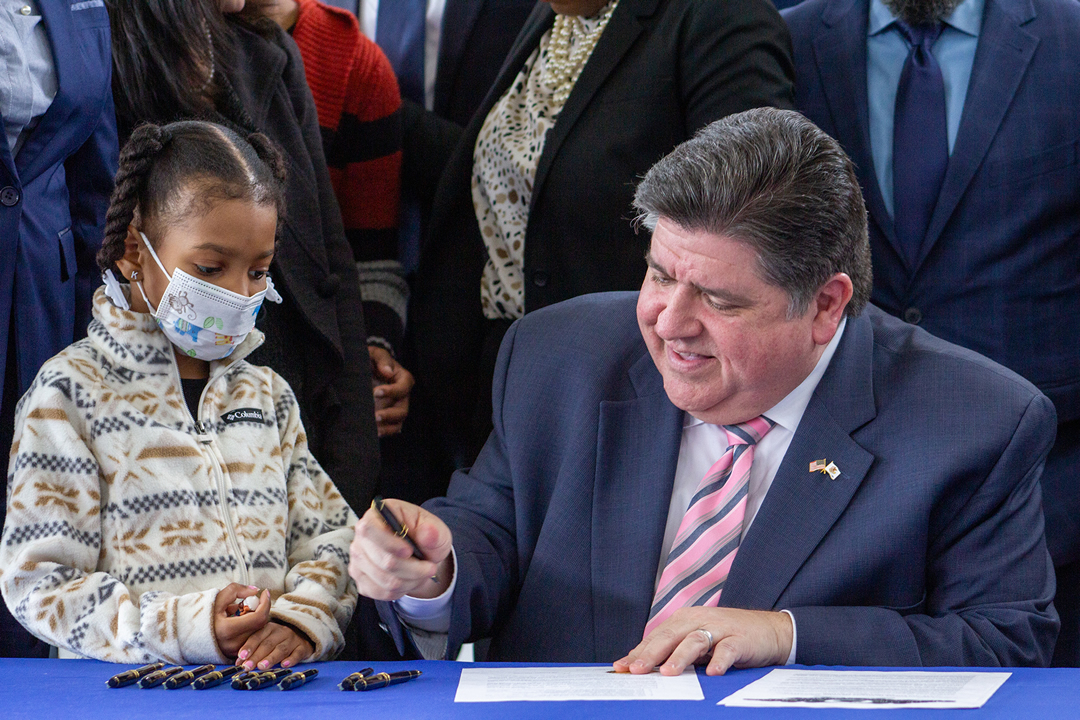 Gov. JB Pritzker alongside 7-year-old Kioko Jenkins