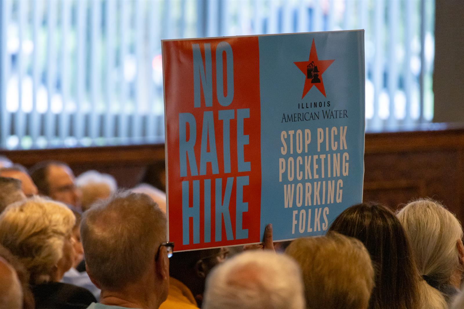 An attendee opposed to water rate increases holds up a sign
