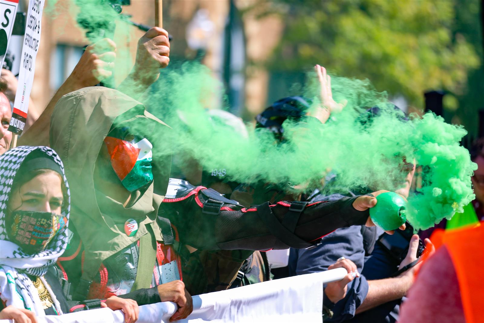 protestor holds up a green smoke bomb