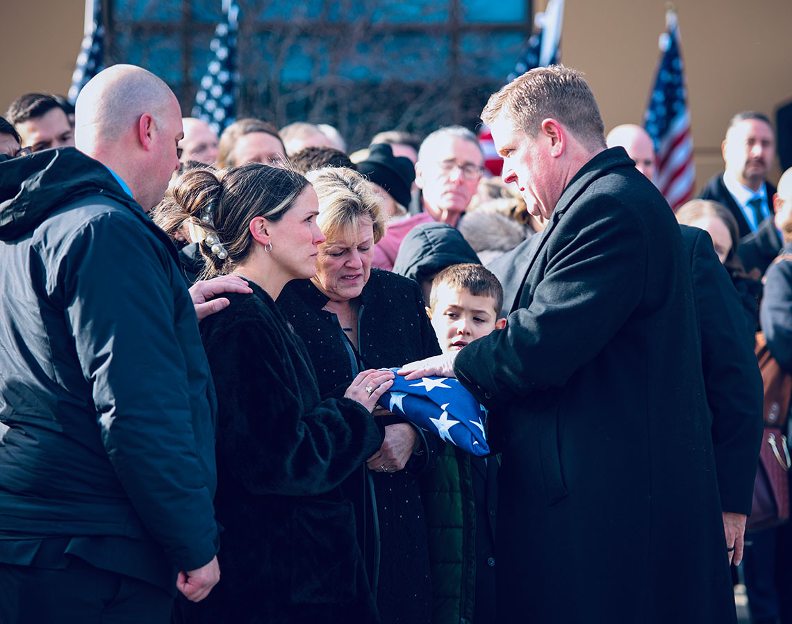 Brendan Kelly hands a flag to Meghan Carns
