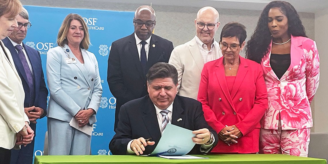 JB Pritzker signs paperwork