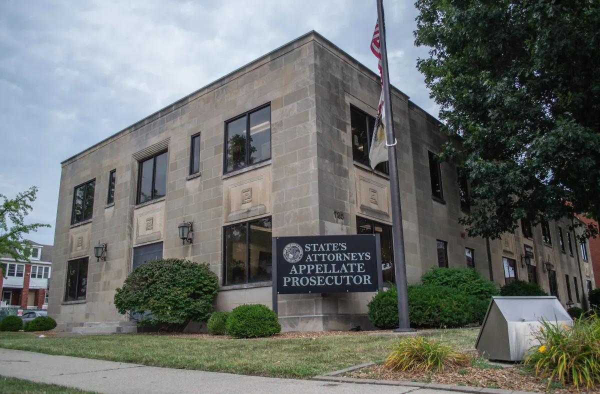 The State's Attorneys Appellate Prosecutor office building, a low stone building behind shrubs and a flagpole.